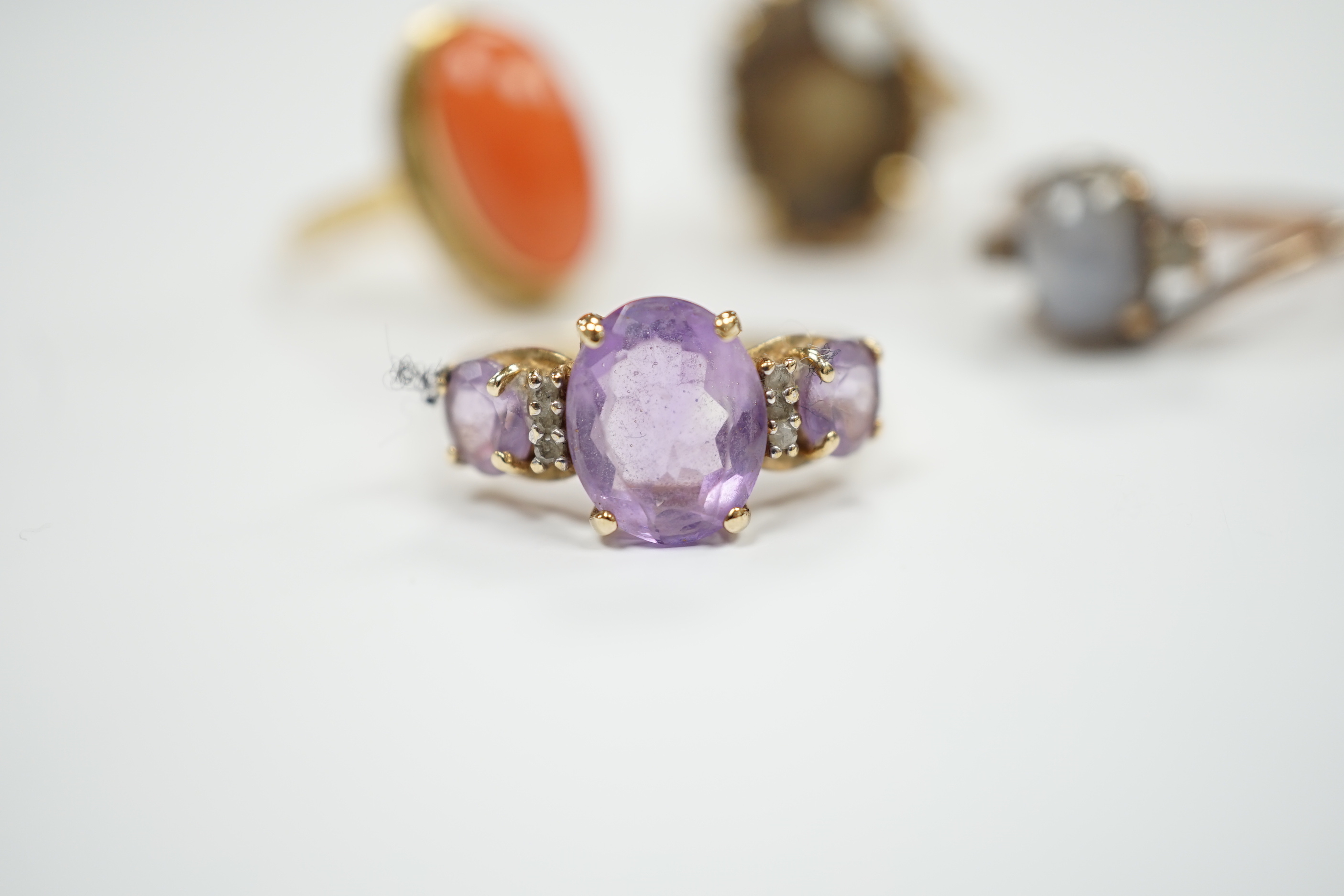 Two modern 10k and gem set rings, including amethyst and diamond chip and two yellow metal and gem set rings including coral set and star quartz? set, gross weight 15.9 grams.